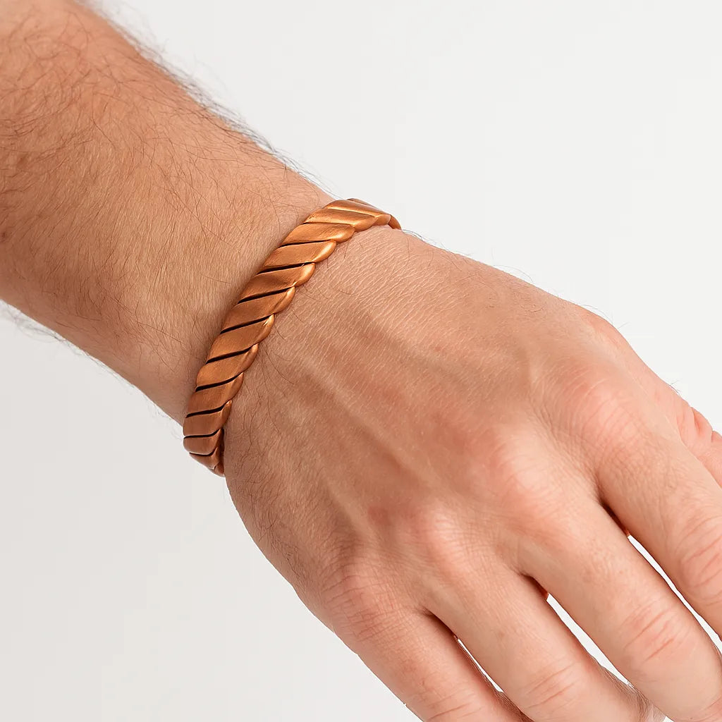 Hand wearing a copper bracelet on a light background