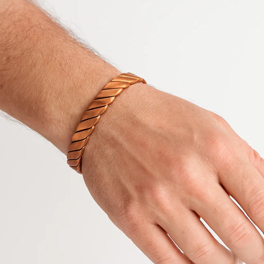 Hand wearing a copper bracelet on a light background