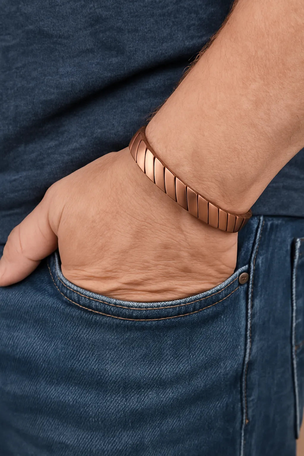 Hand wearing a copper bracelet with blue jeans